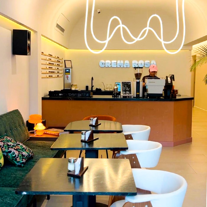 Modern interior of Crema Rosa café in Antigua Guatemala, featuring minimalist decor, stylish seating, and a neon coffee bar.